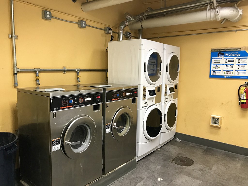 a laundry room with three washing machines and a dryer