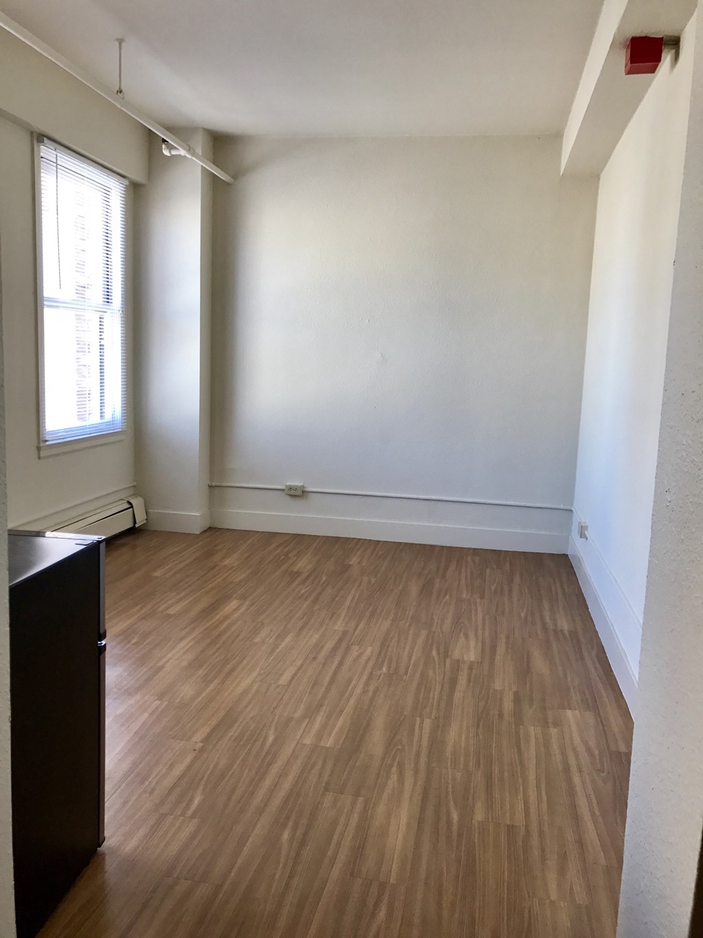 an empty living room with wood flooring and a window