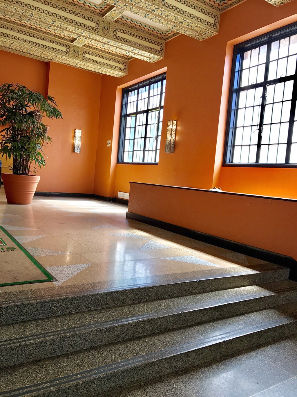 the lobby of a building with orange walls and a potted plant