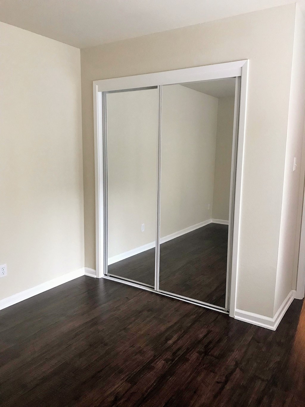 a room with a wood floor and a closet with mirrored doors