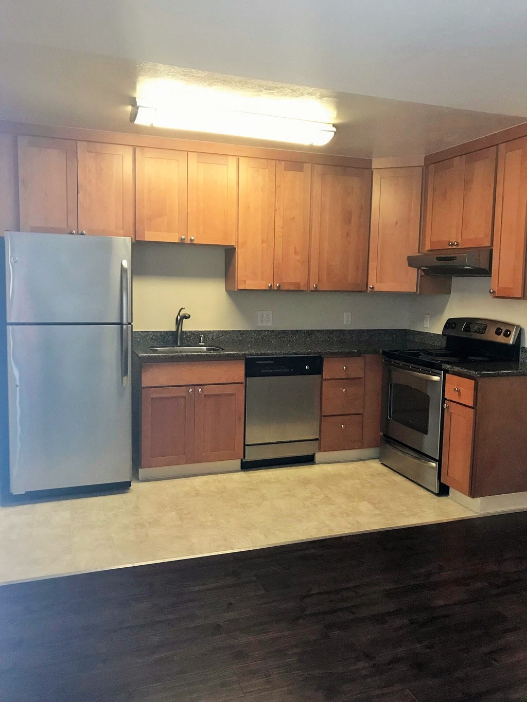 an empty kitchen with wooden cabinets and stainless steel appliances