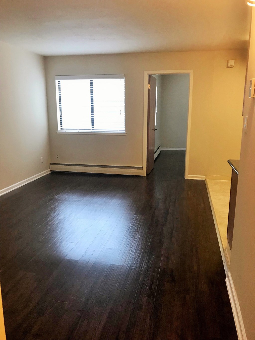 an empty living room with wooden floors and a window