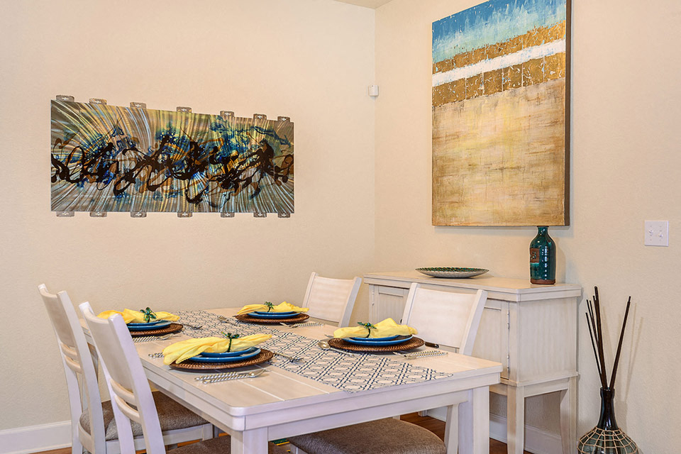 a dining room with a table and chairs and a painting on the wall