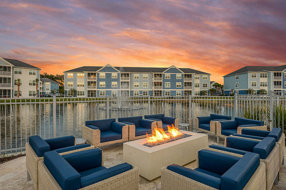 a fire pit overlooking a lake with an apartment building in the background