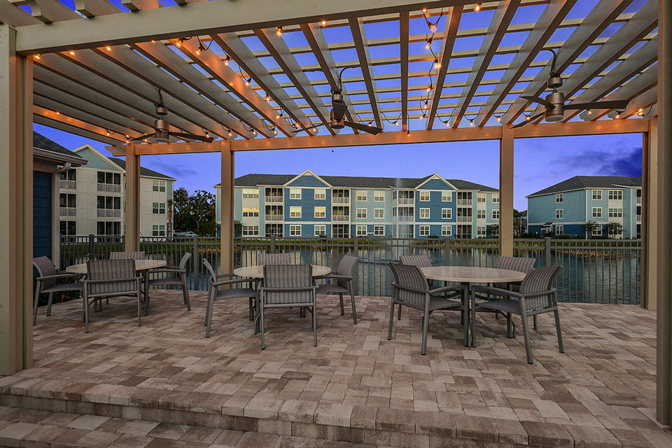 a patio with tables and chairs under a pergola
