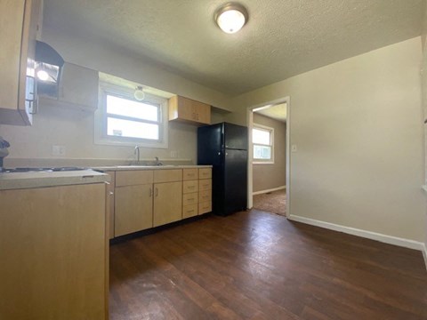 A kitchen with wooden floors and a black refrigerator.