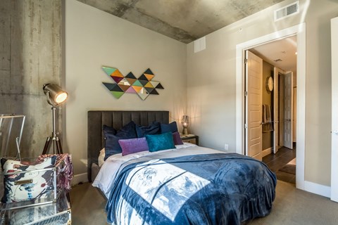 Industrial-inspired bedroom with queen sized bed at The Case Building in Dallas, TX
