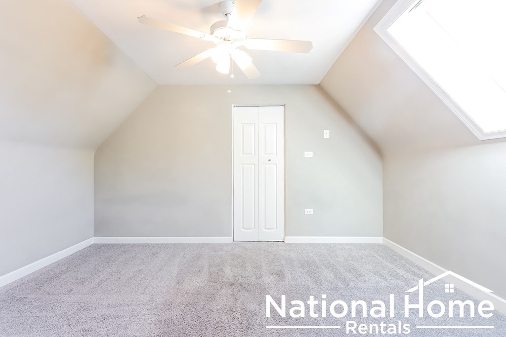 A room with a ceiling fan and a door.
