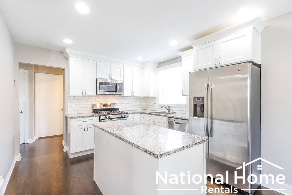 A kitchen with a refrigerator, microwave, and stove top oven.