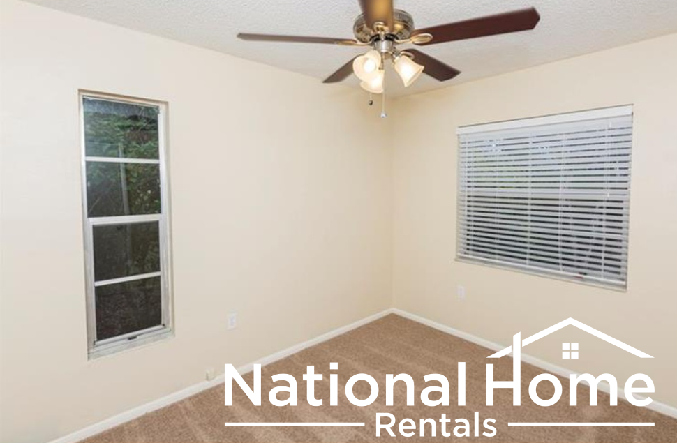an empty room with a ceiling fan and a window