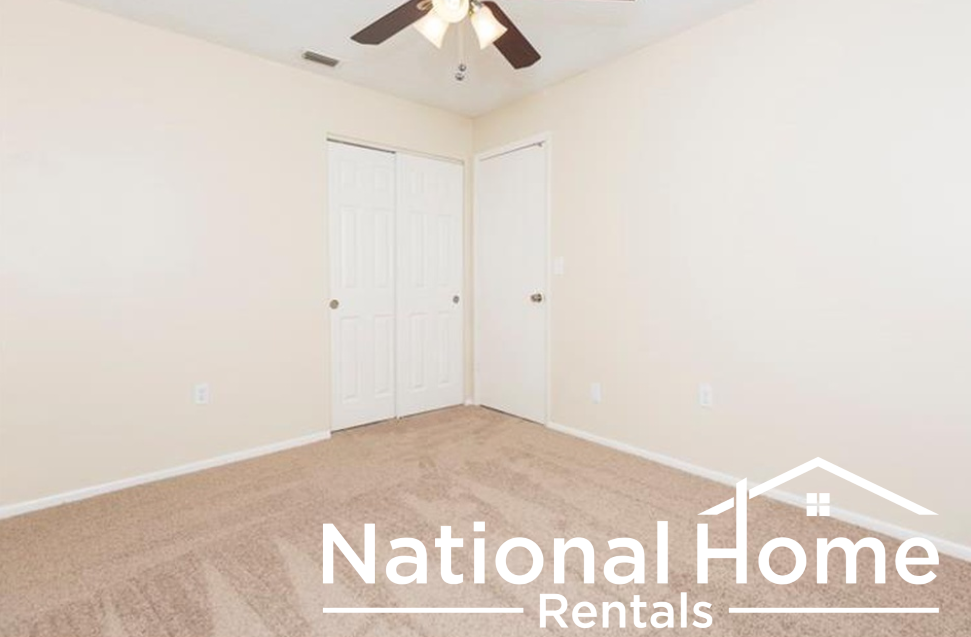 a bedroom with white walls and carpet and a ceiling fan