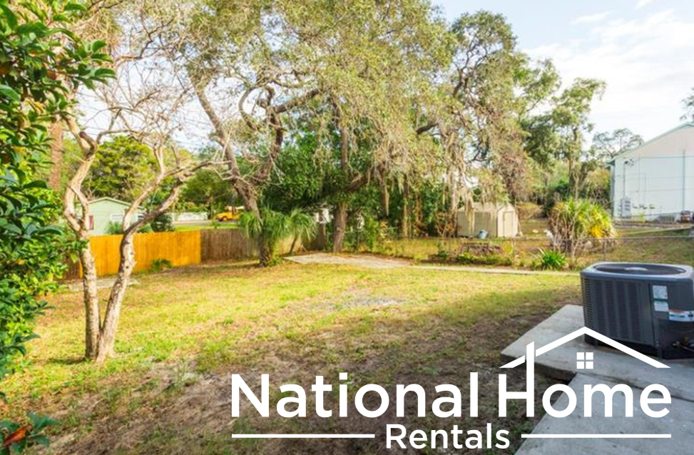 the backyard of a house with a yard and a trash can