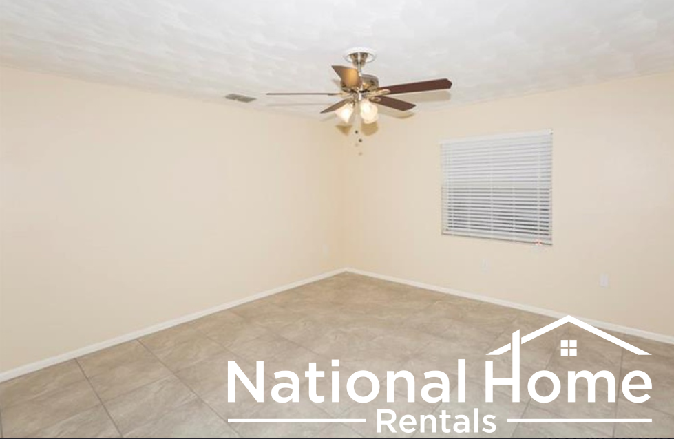 an empty room with a ceiling fan and a window