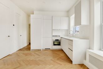a renovated kitchen with white cabinets and a wooden floor