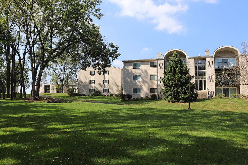 a large building with a green lawn and trees in front of it