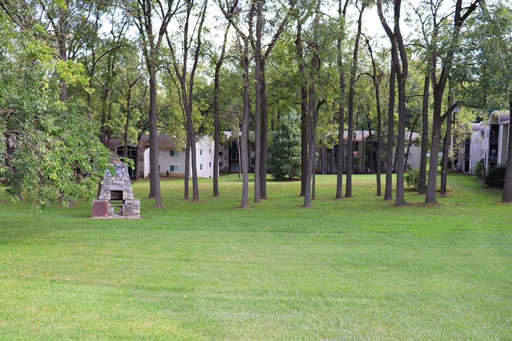 a park with trees and a monument in the grass