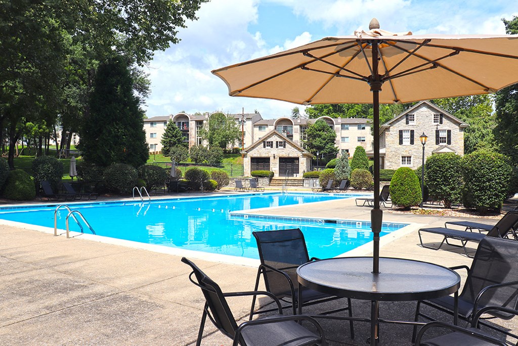 a swimming pool with chairs and a table with an umbrella