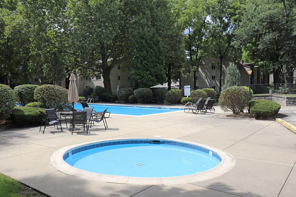 a swimming pool and patio with chairs and umbrellas