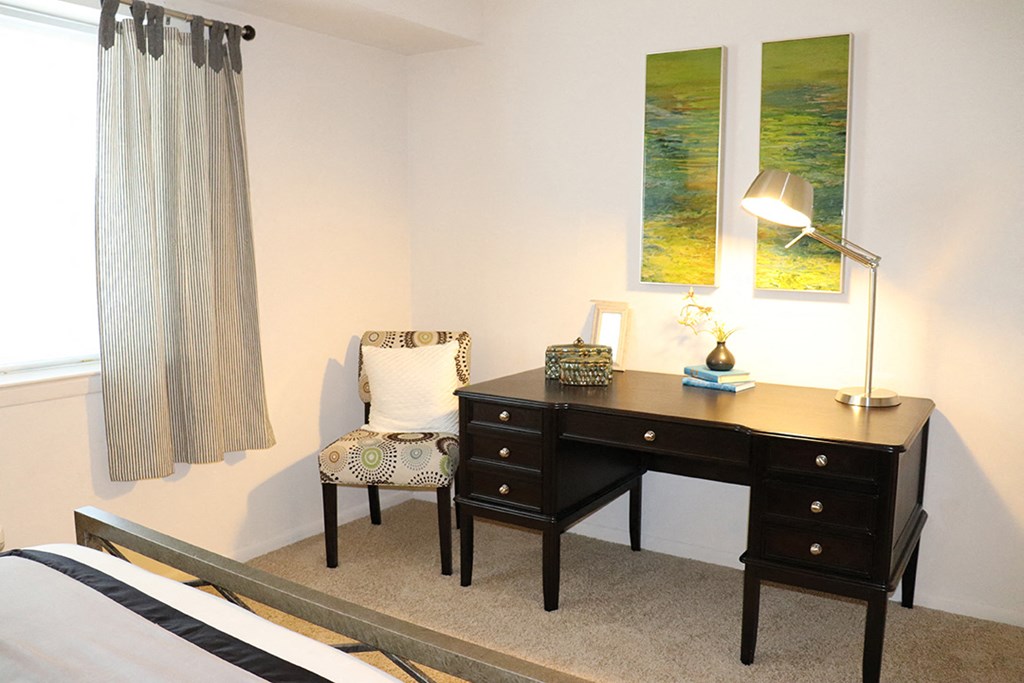 a bedroom with a desk and a chair and a window