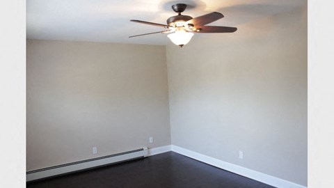 an empty living room with a ceiling fan