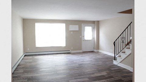 an empty living room with a staircase and a door