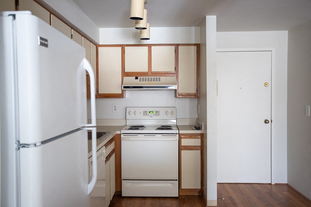 an empty kitchen with white appliances and wooden cabinets