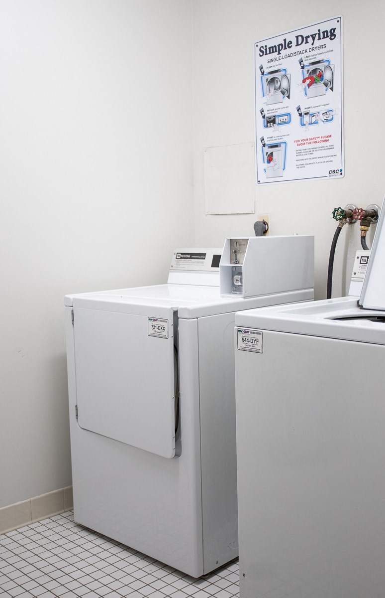 a laundry room with two washer and dryers and a sink