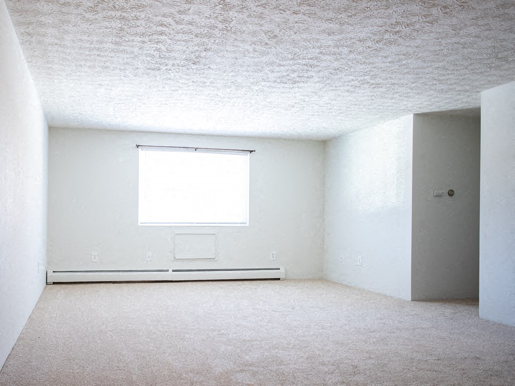 an empty room with a window and white walls