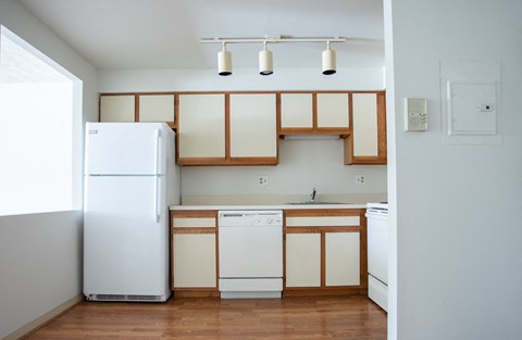an empty kitchen with white appliances and wooden cabinets