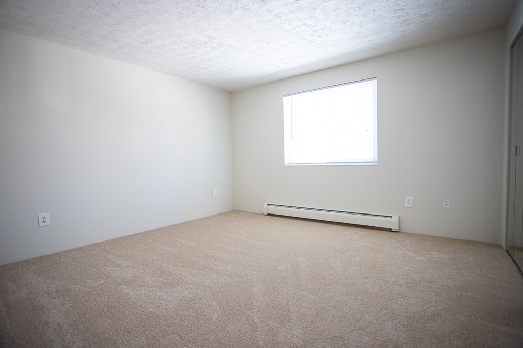an empty room with a window and carpet