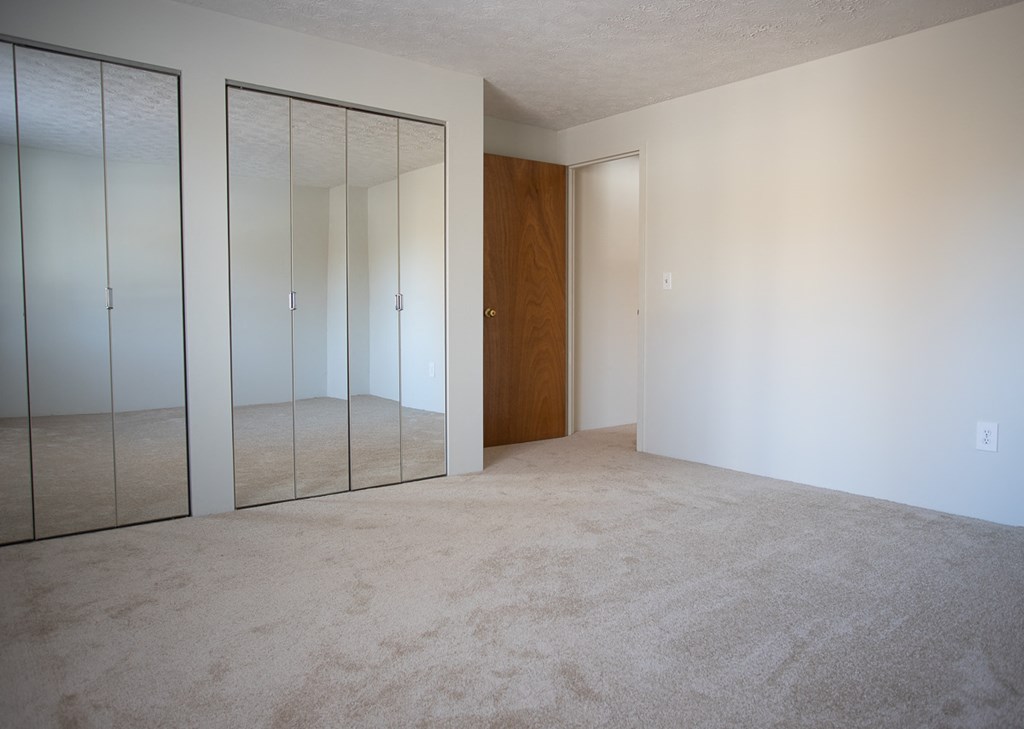 an empty room with mirrored closet doors in it