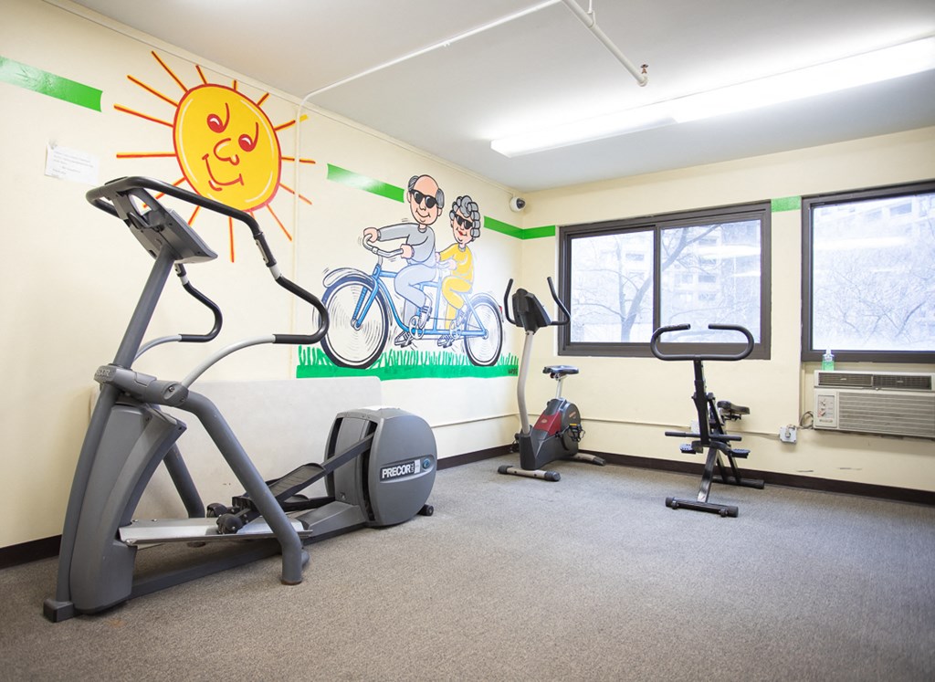 a gym with cardio equipment and a mural on the wall