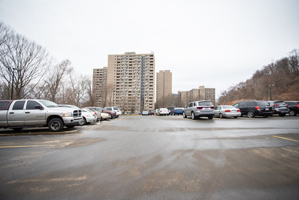 a parking lot full of cars with buildings in the background