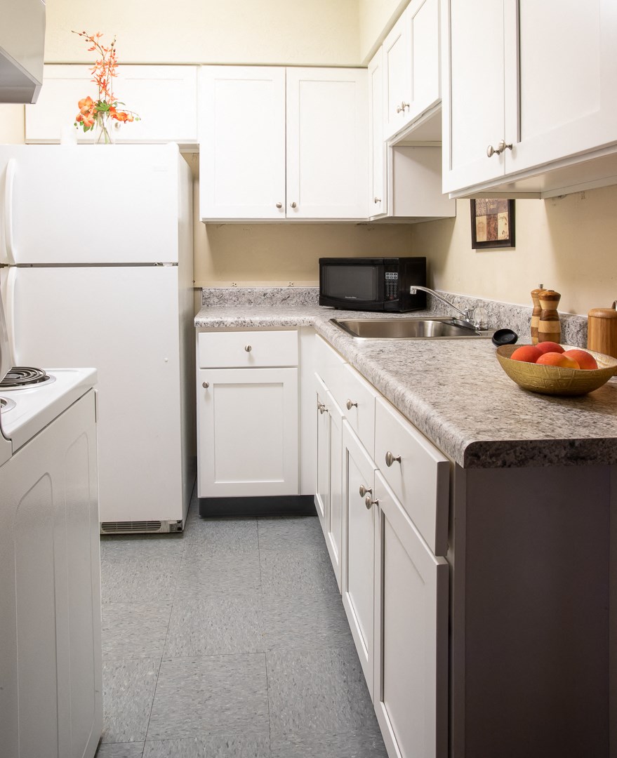 a kitchen with white cabinets and granite counter tops and white appliances