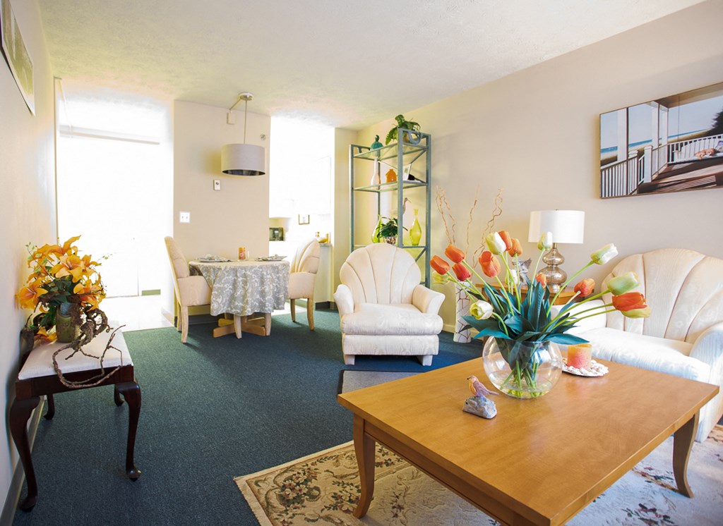 a living room with white furniture and a table with flowers