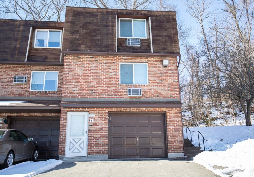 the front of a brick house with two garage doors