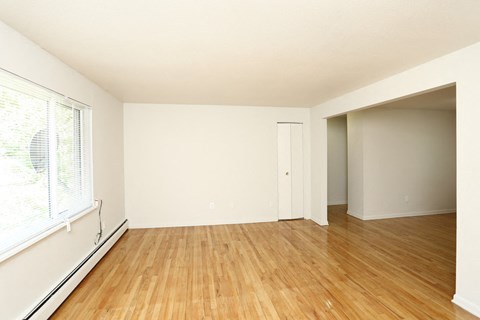 an empty living room with wood floors and a large window