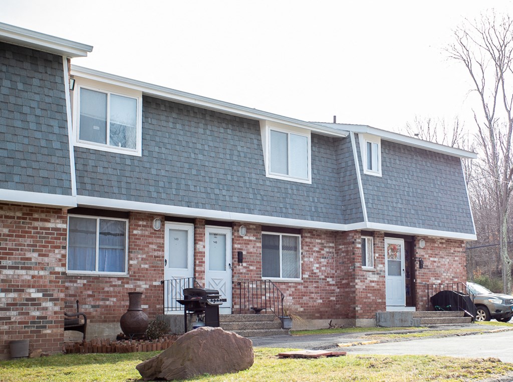 a brick house with a blue roof and white windows