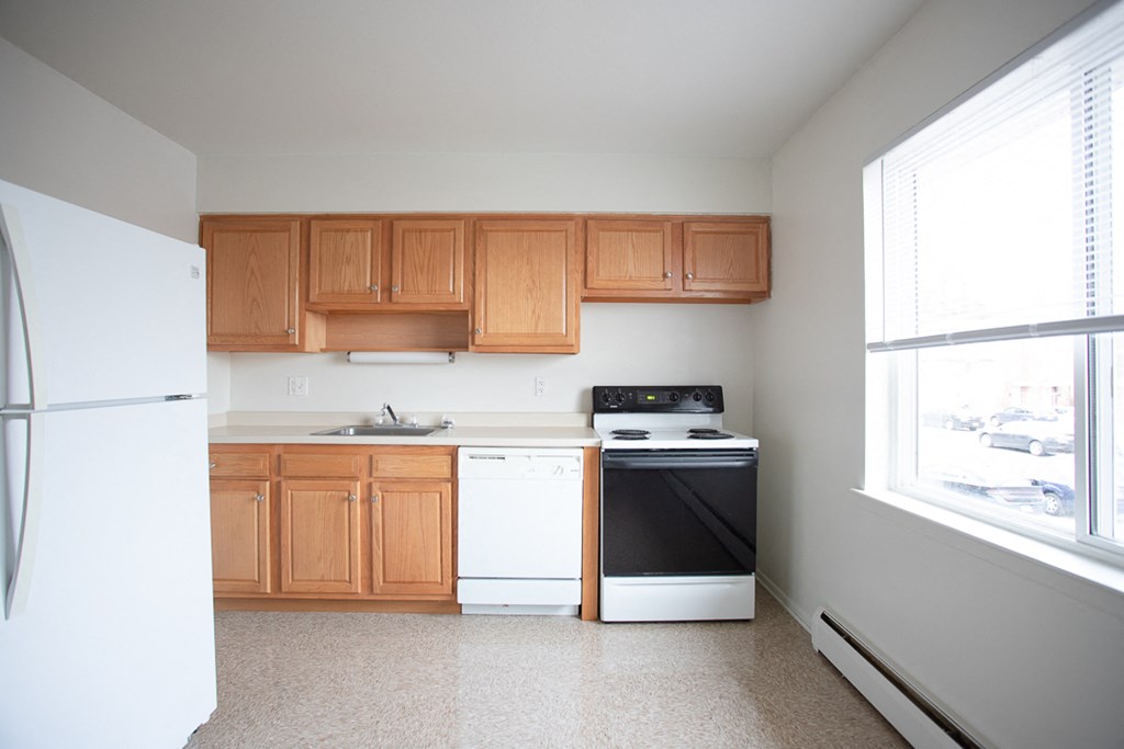 an empty kitchen with wooden cabinets and white appliances