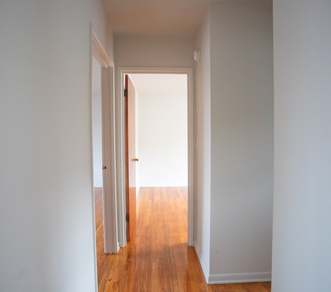 an empty hallway with wood floors and white walls