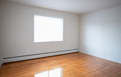 an empty room with wooden floors and a window