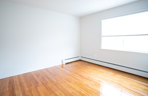 an empty room with wood floors and a large window