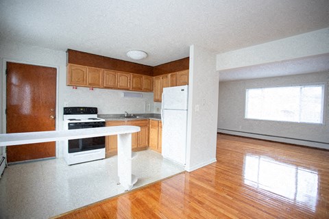 an empty kitchen with wood floors and white appliances