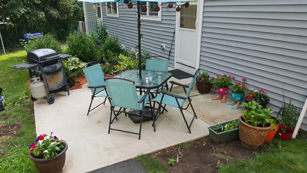 a patio with a table and chairs and a grill
