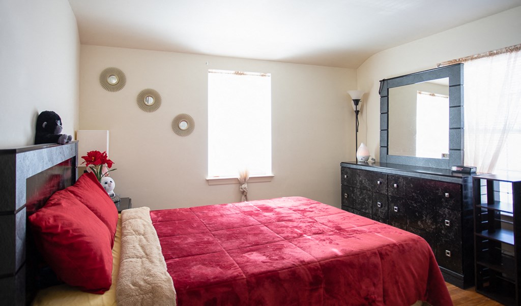 a bedroom with a bed and a dresser and a mirror