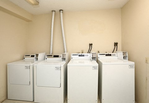 four washers and dryers in a room with a wall