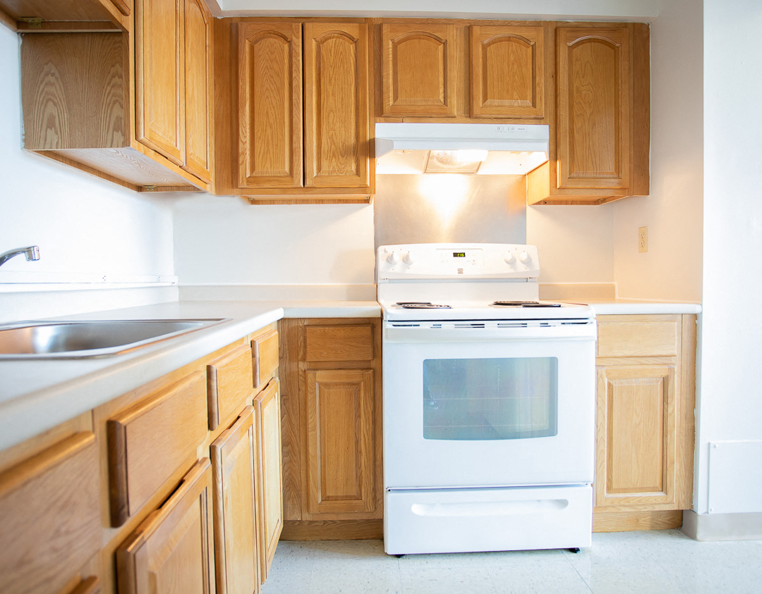 an empty kitchen with wooden cabinets and a white stove