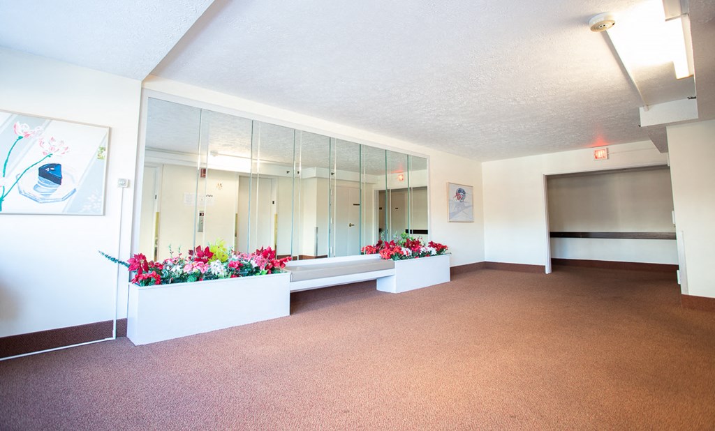 a room with a bench and flowers in front of a mirror