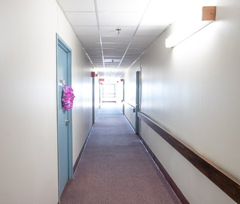 a hallway with white walls and blue doors and a pink flower hanging on the wall