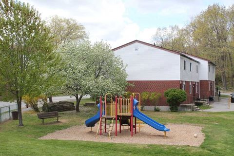 a playground with slides and a picnic table in front of a house